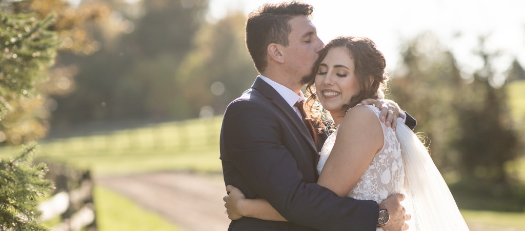 A bride and groom hugging after their wedding ceremony and the groom kissing the bride on the cheek
